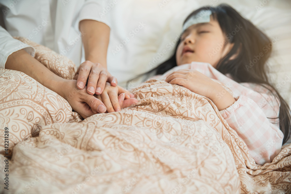 Sick little child with temperature in bed. Hand of mother on his forehead. photo of caring mother holding head on sick daughter forehead. Sick little child with temperature in bed. Hand of mother on his forehead. photo of caring mother holding head on sick daughter forehead.