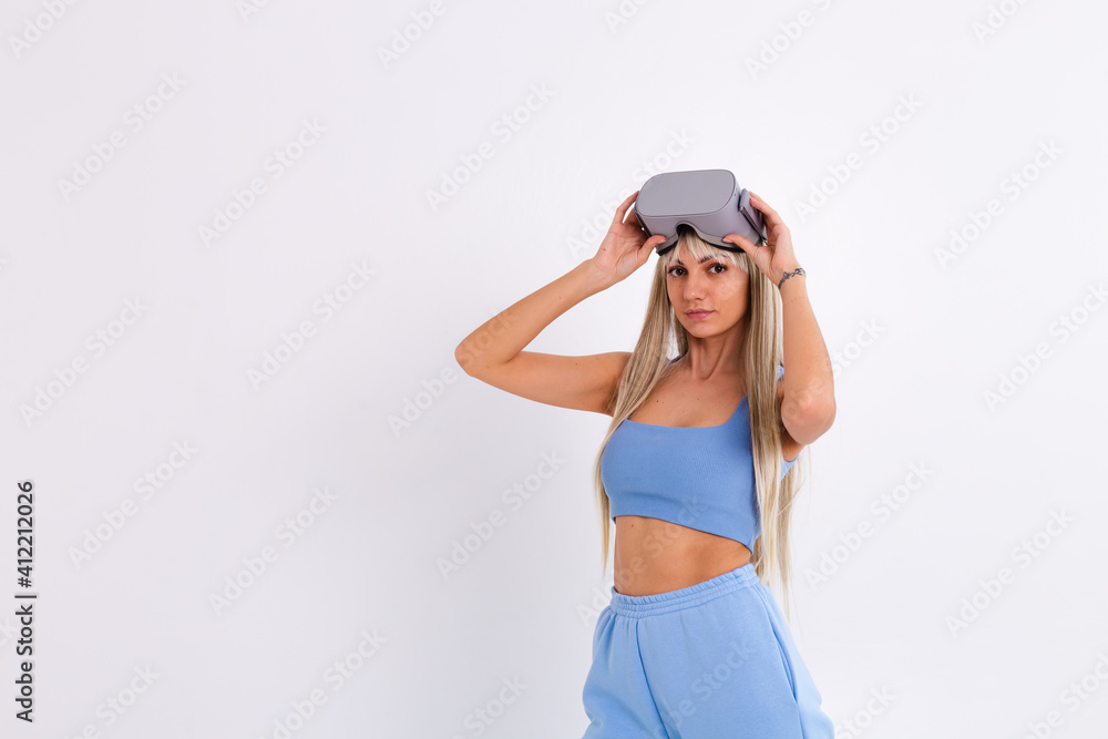 Studio photo of a young attractive woman in a warm blue fashionable suit wearing virtual reality glasses on a white background Studio photo of a young attractive woman in a warm blue fashionable suit wearing virtual reality glasses on a white background