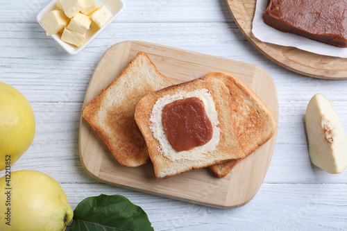 Toasts with delicious quince paste on white wooden table, flat lay photo