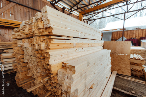 warehouse of wooden boards  background texture of wood harvested for shipment to the factory  finished products of the woodworking industry  many smooth bars of wood