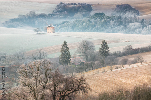Winter landscape with frosted wavy fields, windmill, Moravia, Czech Republic.