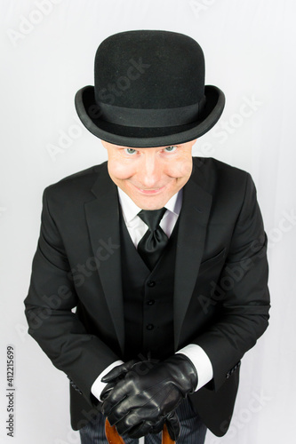 Portrait of Man in Bowler Hat and Dark Suit Smiling. Concept of Classic and Eccentric English Gentleman. British Businessman. Vintage Style and Fashion.