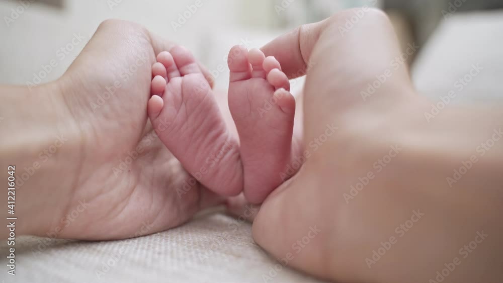 close up father parent hand touching small feet of baby infant when sleeping on soft bed. footprint details. care, love, and protection concept. close up father parent hand touching small feet of baby infant when sleeping on soft bed. footprint details. care, love, and protection concept.