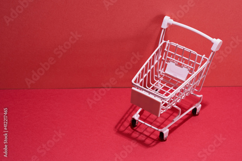 mini shopping cart on the red background with shadow