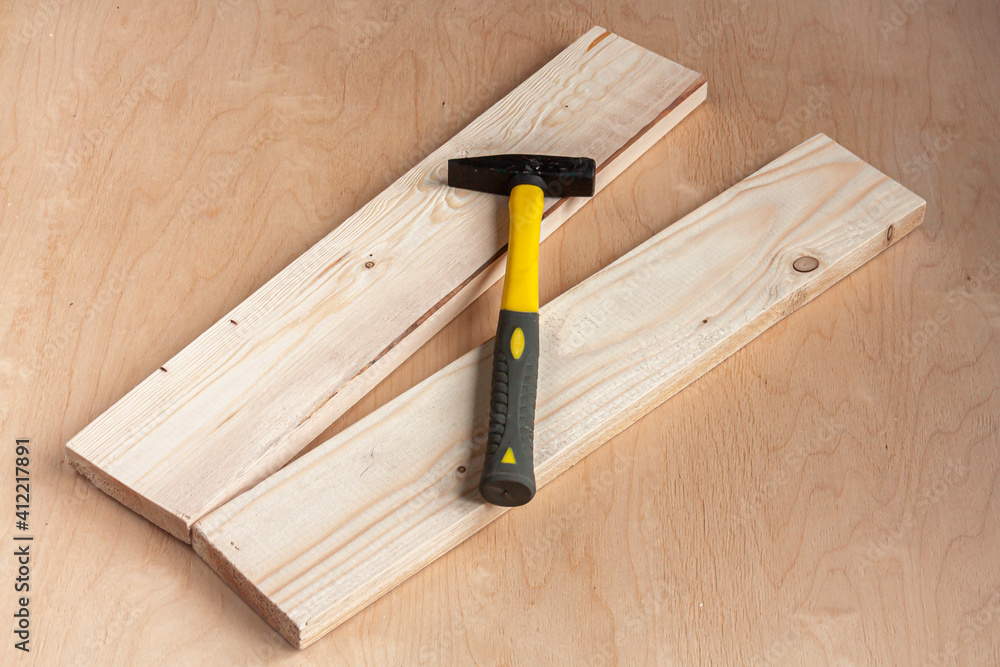 a hammer and two wood boards on wooden background