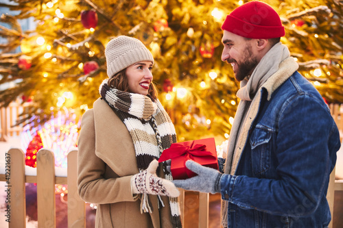 Loving man giving Christmas present to girlfriend outdoors