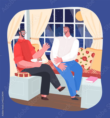 Men friends relaxing at home at evening, eating sweet cake, happy spending leisure time at indoors, brothers talking, relaxing at couch, night city with moon and urban buildings outside window