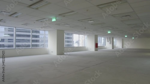 Handheld, camera moving backward – an unfurnished empty office space interior in a city high-rise after tenant move out. COVID-19 cause office space reduction. 