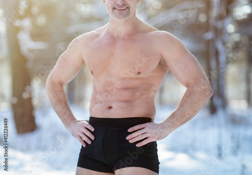 Cold resistance training concept. Unrecognizable senior man with naked torso posing in his underwear at winter park