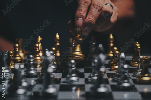 Hand of businessman playing chess figure in competition strategy management and leadership concept