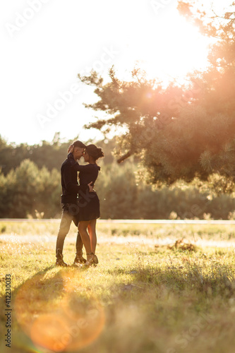 Young couple in love walking in the summer park holding hands. woman and man dressed in black clothes have a date outdoors on sunset. Romantic relationship. Valentines Day © Andriy Medvediuk