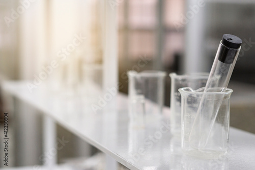 Glass tube and beaker on white table on science laboratory background..