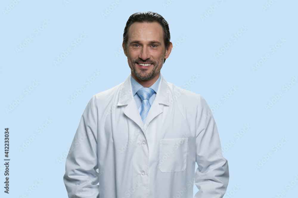 Portrait of smiling middle-aged physician in a white coat. Isolated on blue background. Portrait of smiling middle-aged physician in a white coat. Isolated on blue background.