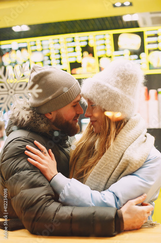 Winter holidays conception. Indoor night portrait of young couple. Posing in a cafe of European city.