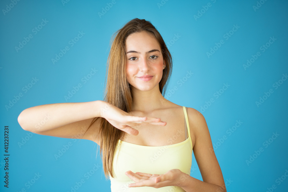Portrait of a smiling girl holding copy space on her palm isolated over blue background Portrait of a smiling girl holding copy space on her palm isolated over blue background