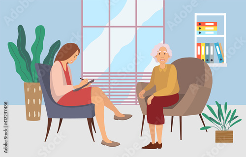 Patients at a reception at the psychotherapies. Elderly woman talking to psychotherapist or psychologist and answer questions. Female sits in a chair, listens and writes to the client's problems