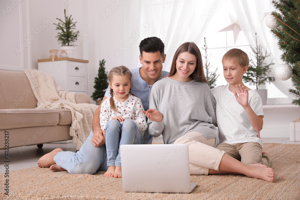 Family with children using video chat on laptop in room decorated for Christmas Family with children using video chat on laptop in room decorated for Christmas