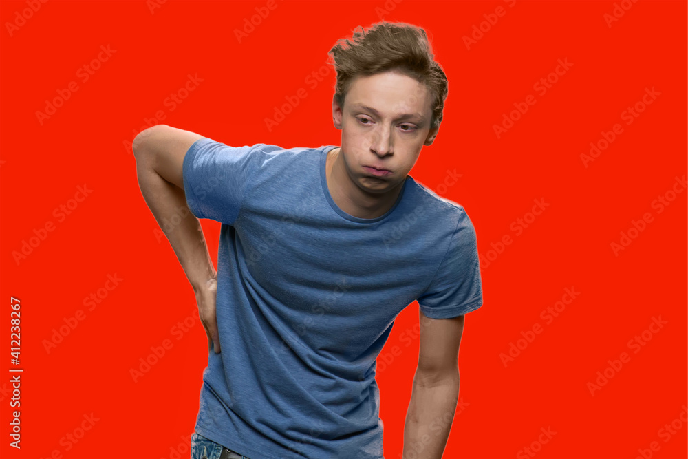 Sick guy with back pain. Exhausted young guy is touching his lower back isolated on red background. Sick guy with back pain. Exhausted young guy is touching his lower back isolated on red background.