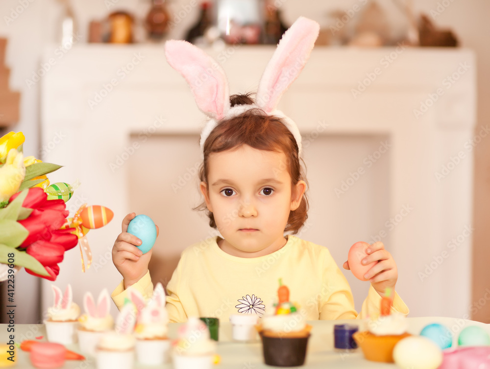 Funny girl child wearing bunny ears and with Easter egg in hand at home. Funny girl child wearing bunny ears and with Easter egg in hand at home.