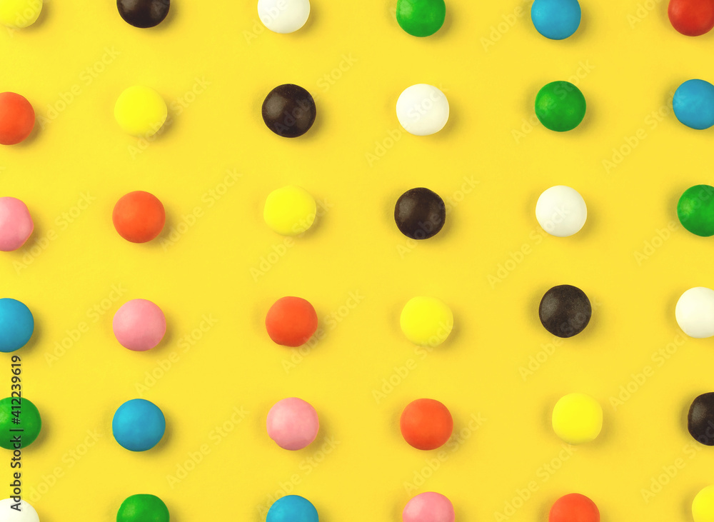 Colorful candies on yellow background. Pattern  from sweets in colored glaze. Creative geometric bright wallpaper
