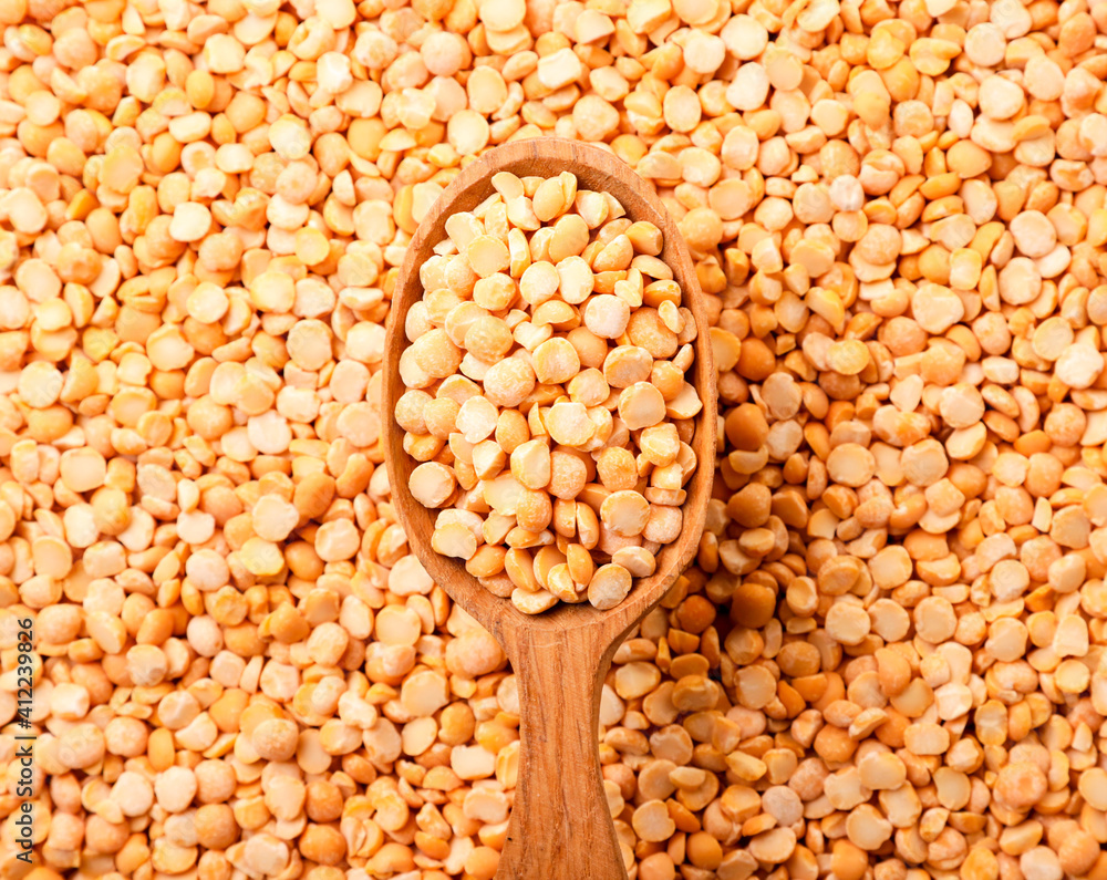 Yellow peas in a wooden spoon on a background of peas. Top view Yellow peas in a wooden spoon on a background of peas. Top view