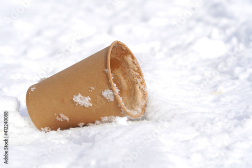 Paper cup of recycled cardboard lies on the snow