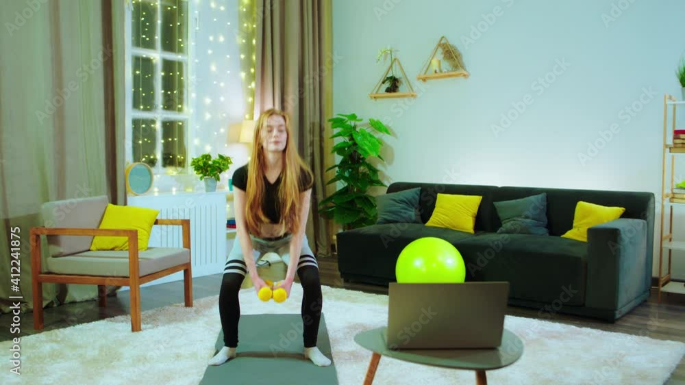A young girl in a very nicely lit room, she is working out on the mat