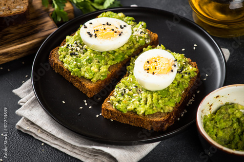 Avocado Sandwiches with Boiled Egg and Cereal Bread in black plate. Healthy snack or breakfast.
