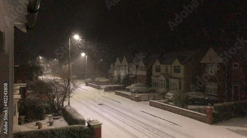 Snow falling at night on a street in England, United Kingdom