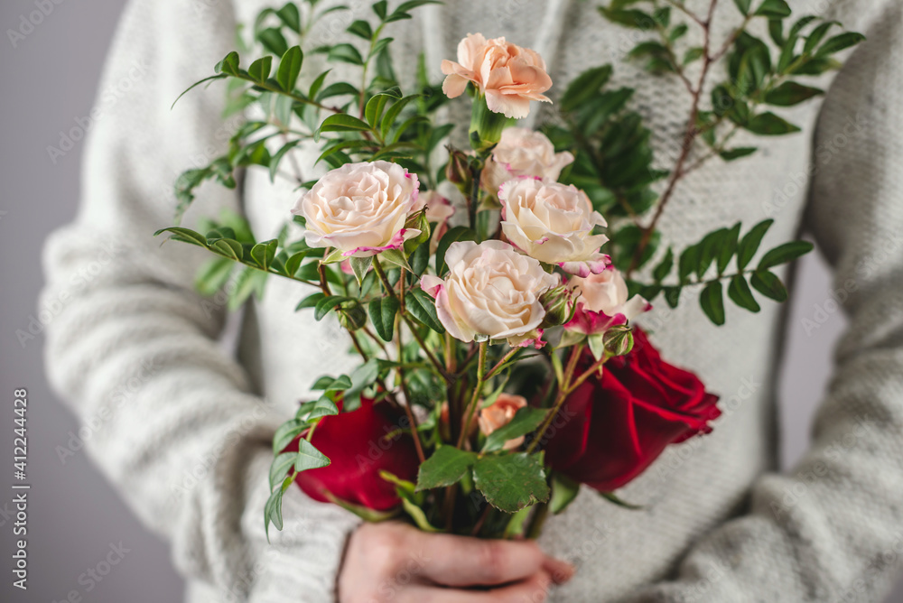 Fototapeta premium A woman in a sweater is holding a tenderness bouquet of flowers. Concept of springtime and a pleasant romantic mood. Closeup