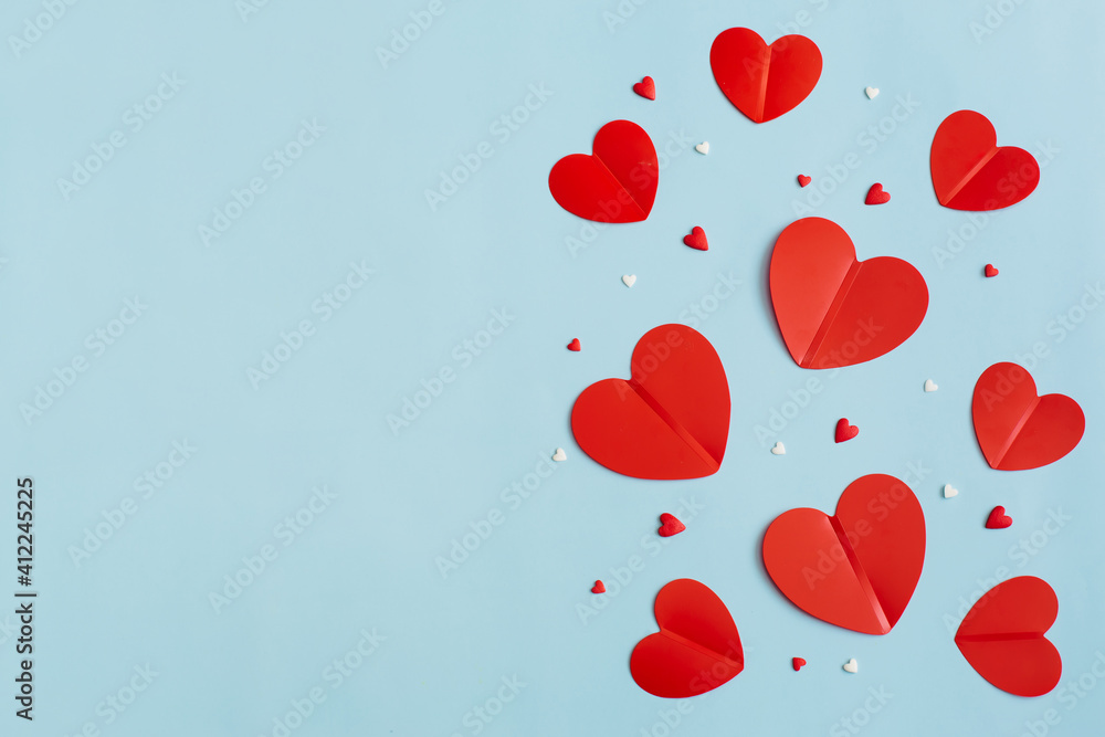 Obraz premium Valentine's Day background February 14th. Confetti, red hearts of paper on pastel blue background. Valentines day concept. Flat lay, top view, copy space.
