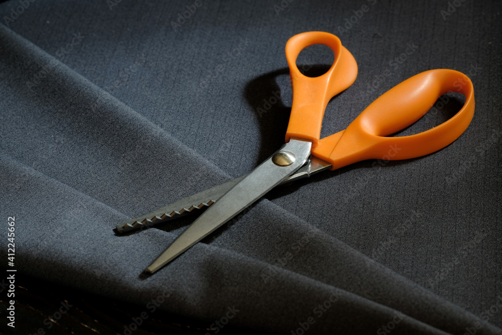 Obraz premium Tailor's scissors lie on the surface of a piece of woolen fabric, close-up, top view. Tailoring.