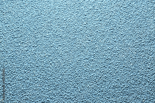 Blue granular mineral fertilizer as background, top view