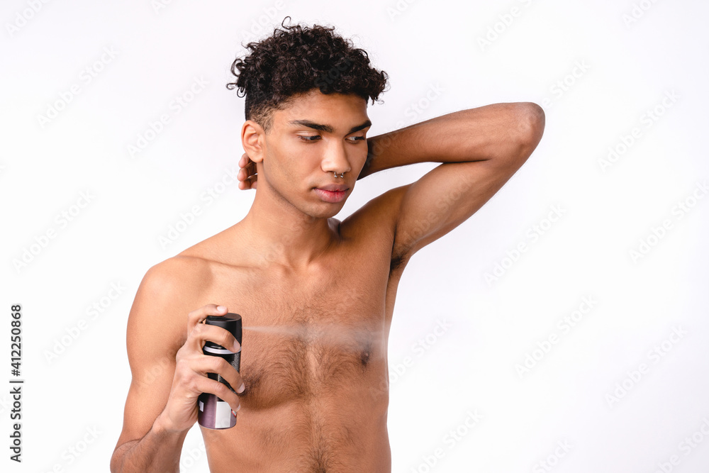 Fototapeta premium Shirtless sexy young afro man using body spray isolated over white background