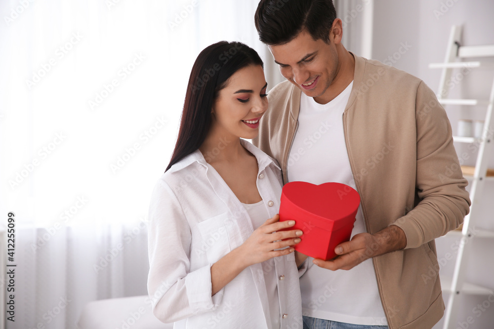 Lovely couple with gift box at home. Valentine's day celebration Lovely couple with gift box at home. Valentine's day celebration