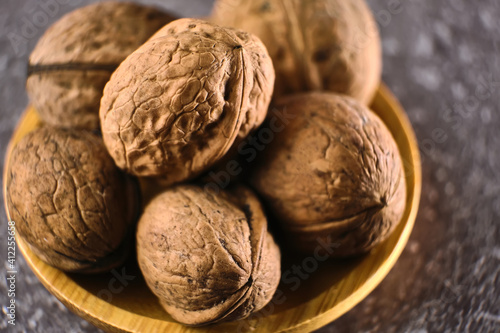Walnut in wooden bowl on black background with copy space