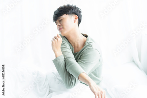 Young Asian man wakes up in bed one early morning