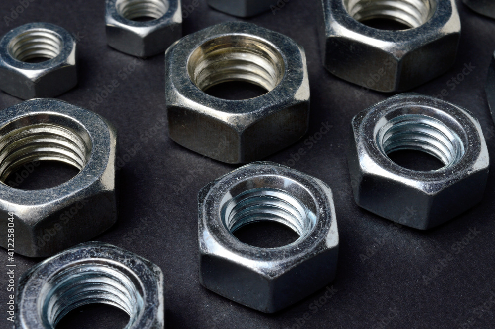 new chrome nuts of different sizes are laid out against a dark background. close-up. new chrome nuts of different sizes are laid out against a dark background. close-up.