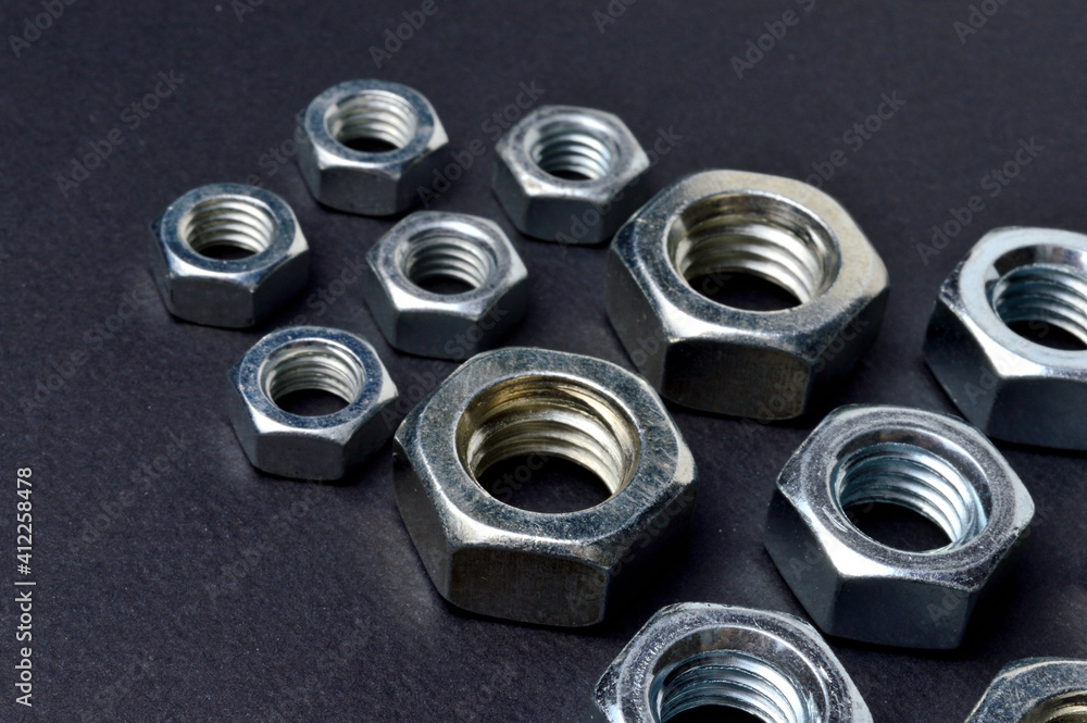 new chrome nuts of different sizes are laid out against a dark background. close-up. new chrome nuts of different sizes are laid out against a dark background. close-up.