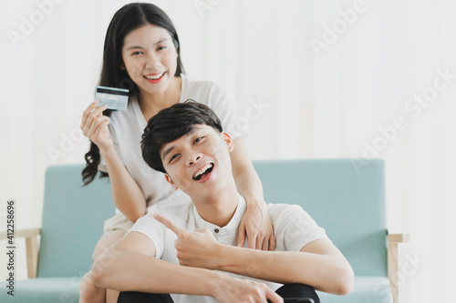 Young couple sitting holding credit card and phone with happy expression