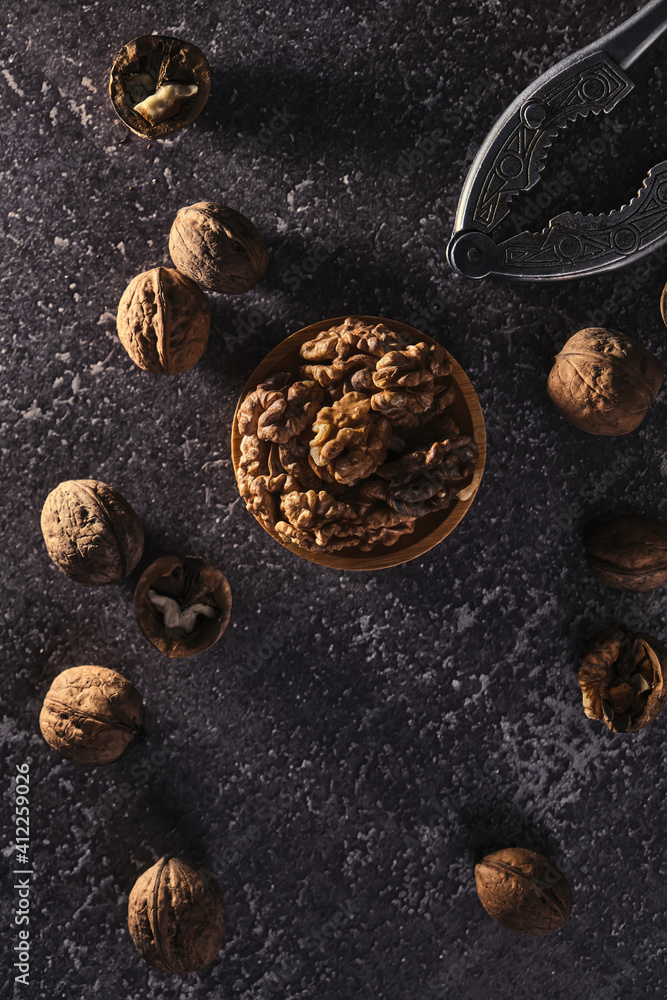 Vintage walnut cracker and walnuts on a dark texture background.