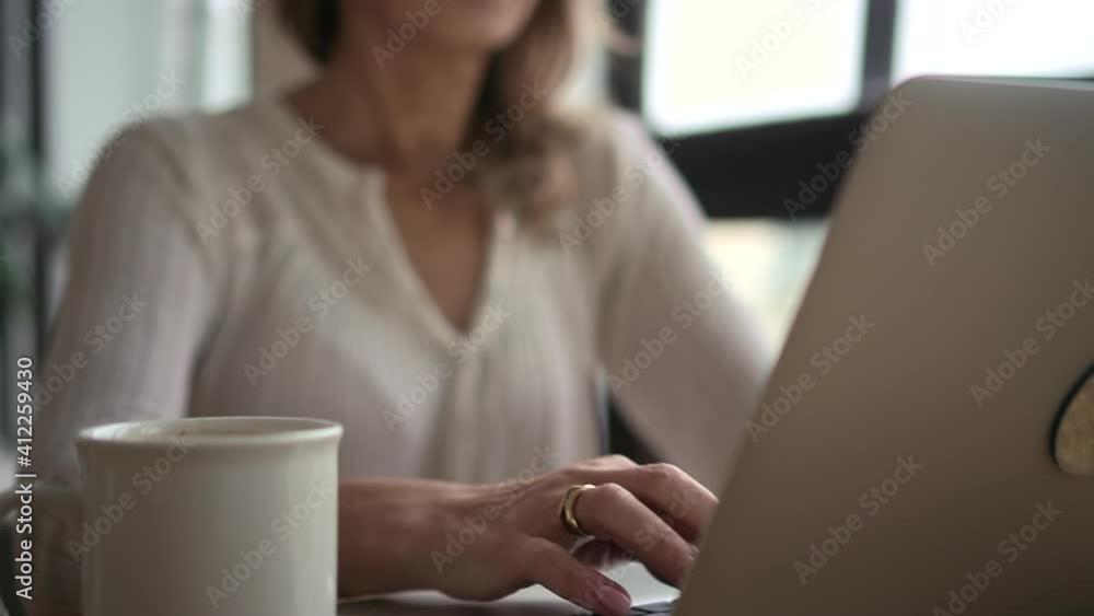 Mature business woman using laptop computer at workplace office. Middle aged condifent employee 50s executive boss wear glasses typing on pc at home from office. Coffee at desk. Mature business woman using laptop computer at workplace office. Middle aged condifent employee 50s executive boss wear glasses typing on pc at home from office. Coffee at desk.