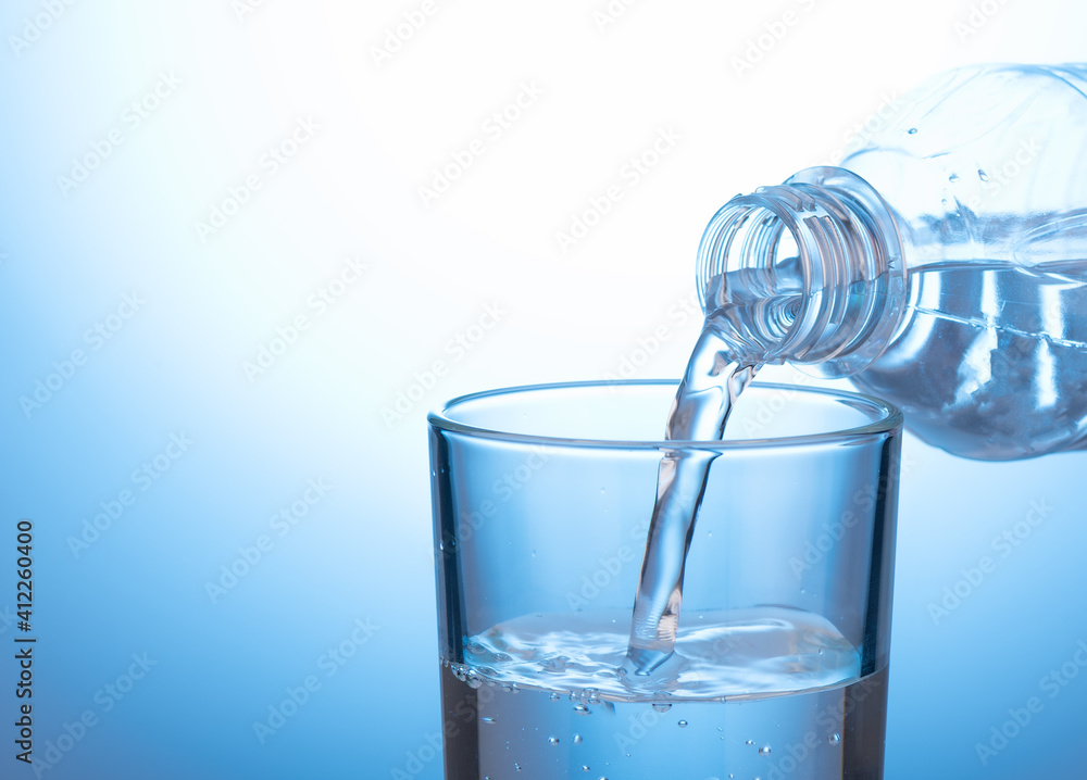 Pouring water from a plastic bottle into a glass beaker. Close up. Pouring water from a plastic bottle into a glass beaker. Close up.