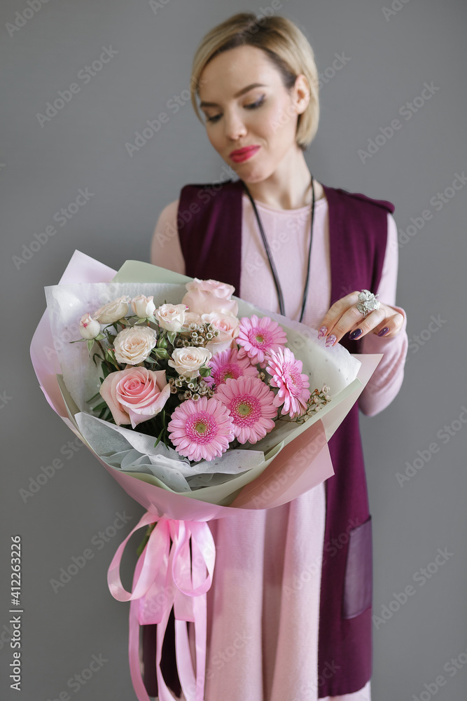 image of a girl in apron holding a flower in her hands with a manicure on a grey background image of a girl in apron holding a flower in her hands with a manicure on a grey background