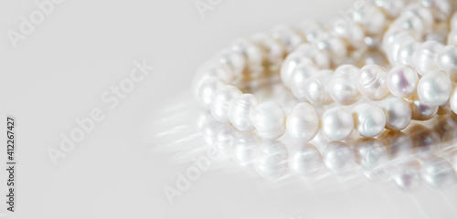 A necklace of white pearls on a glass surface with a place for text.
