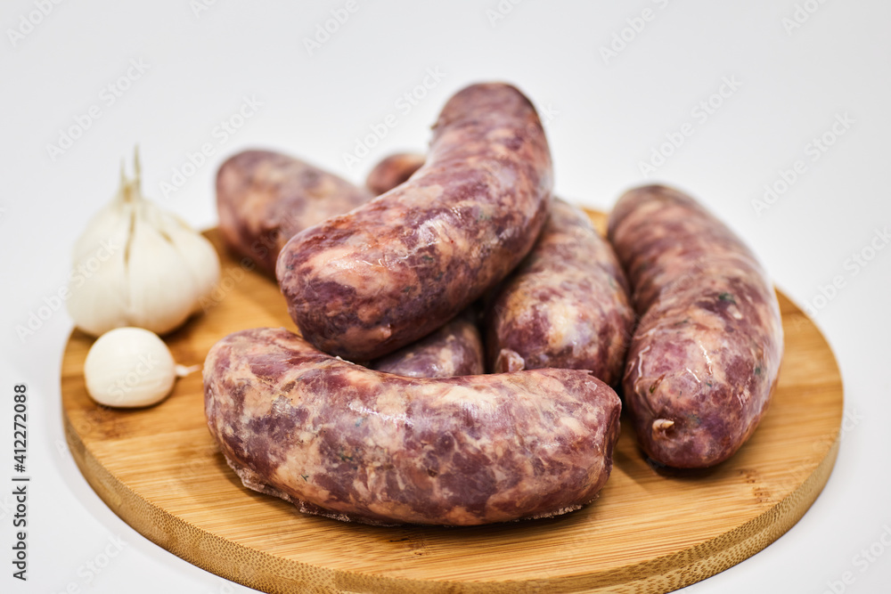 Raw sausage semi-finished products lie on a wooden board, isolated on a white background. The concept of cooking from semi-finished products. Italian traditions, Bavarian sausages, German sausages