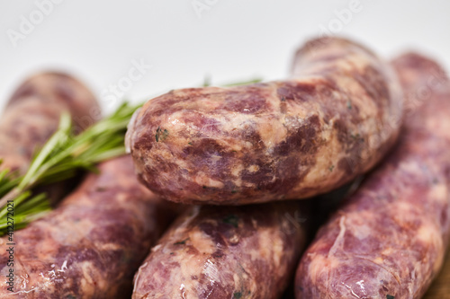 Raw sausage semi-finished products lie on a wooden board, isolated on a white background. The concept of cooking from semi-finished products. Italian traditions, Bavarian sausages, German sausages