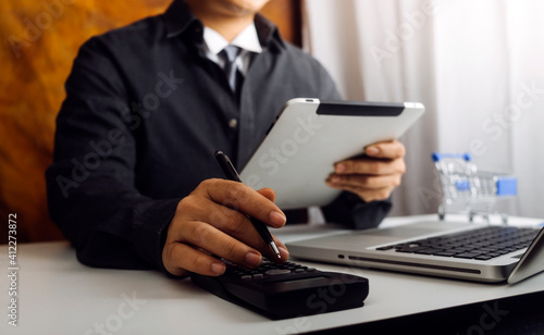 Businesswomen hands working with finances about cost and calculator and laptop with tablet, smartphone at office in morning light