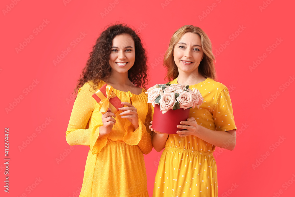 Beautiful women with flowers and gift on color background. International Women's Day celebration Beautiful women with flowers and gift on color background. International Women's Day celebration