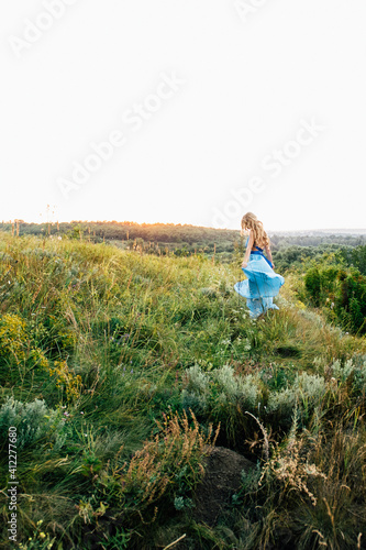 Fototapeta Naklejka Na Ścianę i Meble -  blonde girl with loose hair in a light blue dress and a guy in the light of sunset